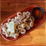 Calamari - Flash fried calamari served with a lemon slice on the top and dill aioli sauce on the side.