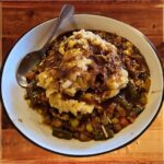 Shepherd’s Pie - A bowl of Barrington's Shepherd’s Pie filled with a savory blend of lamb and beef, slow-cooked with, carrots, peas, and green beans in a rich Guinness and red wine gravy topped with colcannon mashed potatoes.