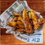 Fish & Chips - Two thick, golden pieces of beer-battered Atlantic haddock served with crispy English “chips”, accompanied by tangy tartar sauce and a rich curry dipping sauce on the side.