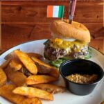 Lamb and Beef Burger - Lamb and Beef Burger Topped with Guinness onions and Dubliner cheddar cheese, lettuce, and tomato, with English “chips” and stone ground mustard on the side.