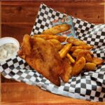 Fish & Chips - A serving basket of a tender piece of battered Atlantic haddock , served with crispy wedge fries, creamy ranch dipping sauce, and a satisfying snack.