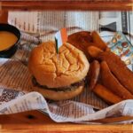 Burger & Chips - A serving basket with a quarter pound Black Angus beef patty, served with golden-brown wedge fries, creamy ranch dipping sauce and a tasty snack.