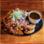 Irish Nachos - Wedge-cut fries generously topped with tender corned beef, sautéed onions, and melted Dubliner cheddar cheese, with a side of savory onion gravy.